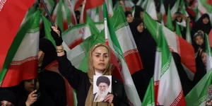 Mulher iraniana acena com a bandeira nacional do Irã enquanto segura uma foto do